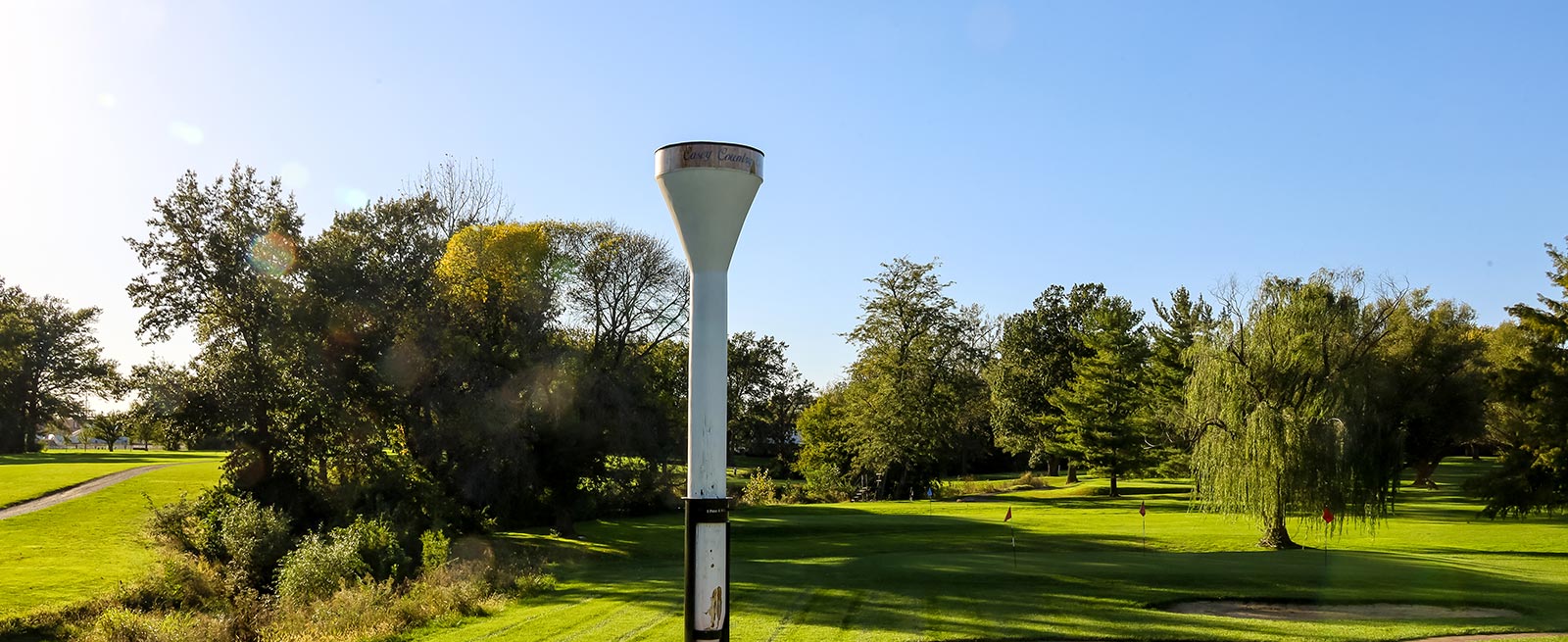 World's Largest Golf Tee standing vertical surrounded by green grass ad trees.