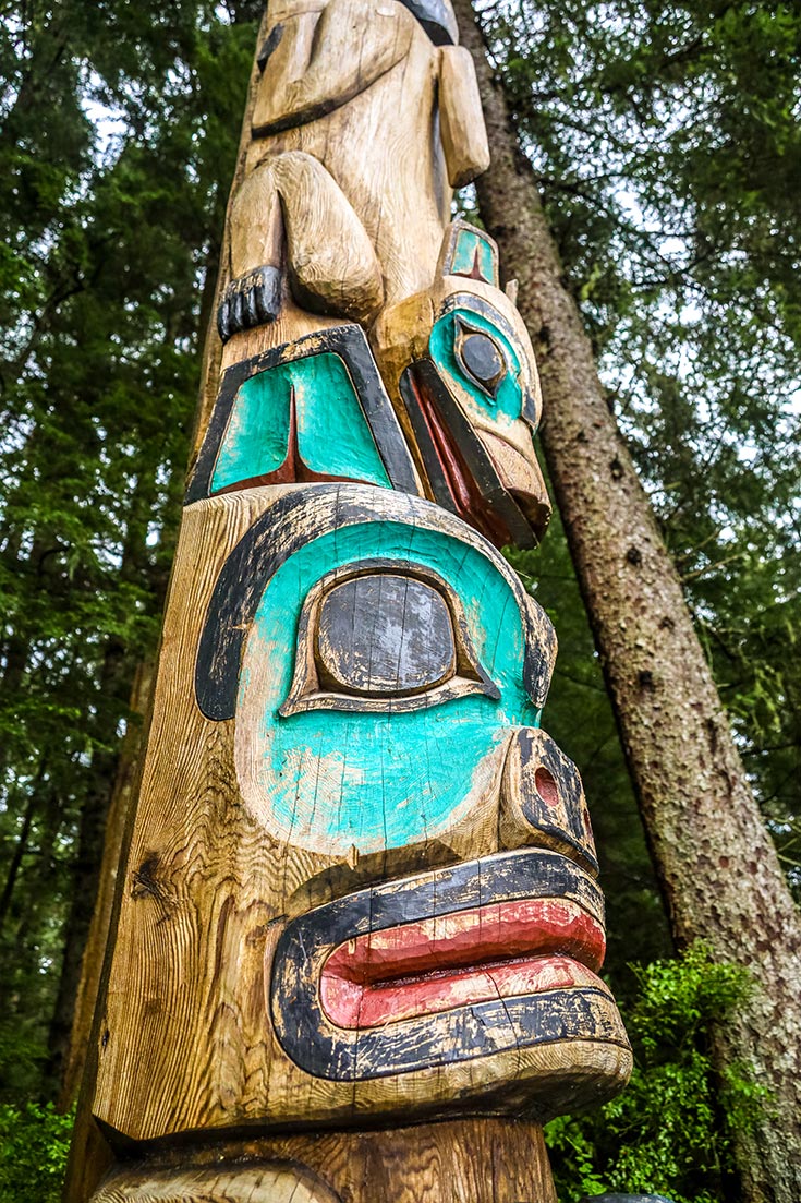 A totem pole standing among trees at Sitka National Historical Park, featured on Exploring States.